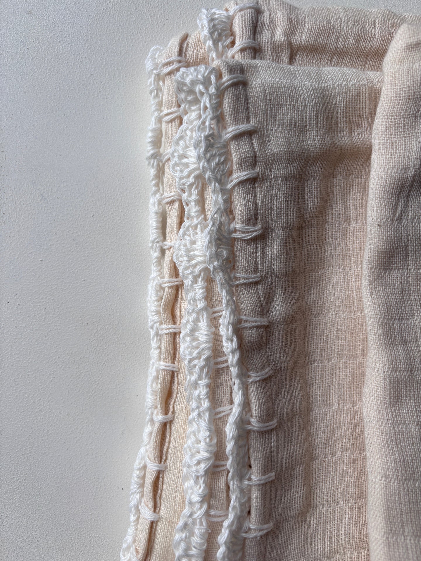 image shows the crochet detail on a cream baby swaddle