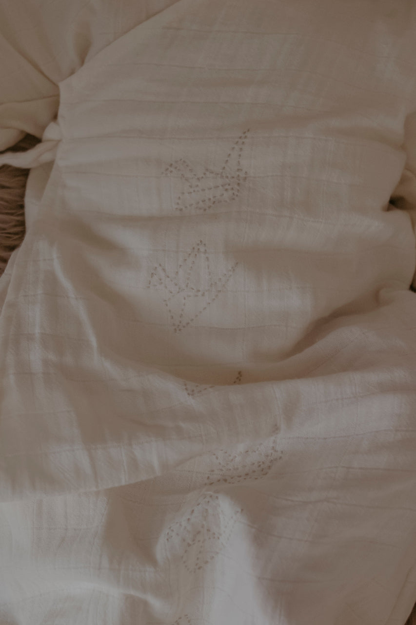 Close-up of organic cotton muslin baby nightgown with detailing.and embroidery