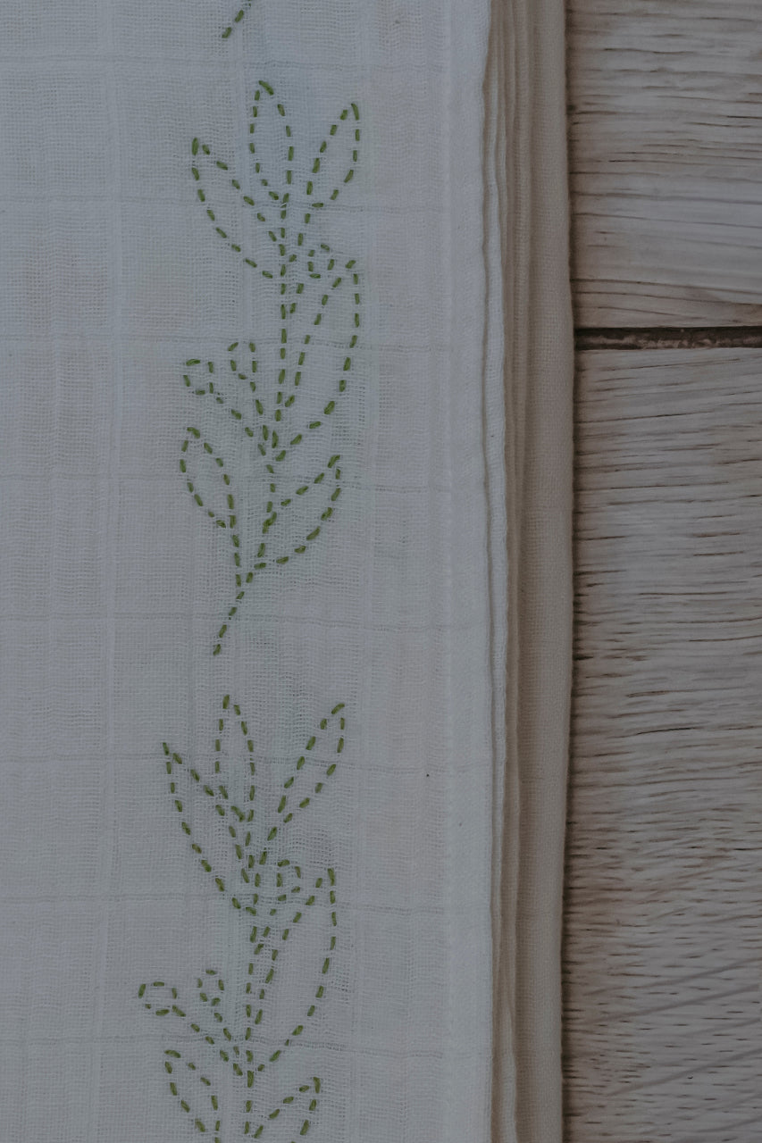 Close-up of a floral embroidery pattern on muslin swaddle