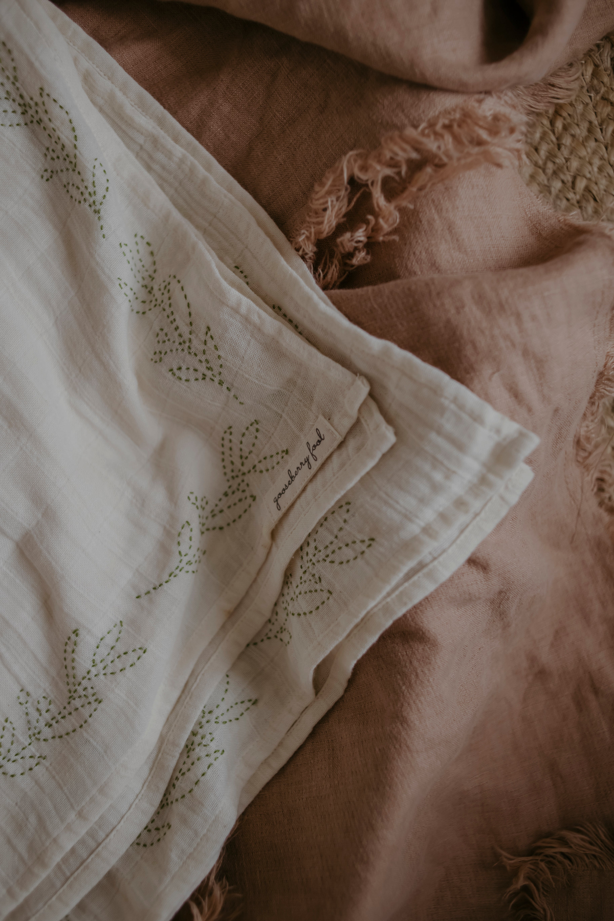 cream organic muslin with green embroidery on a textured surface