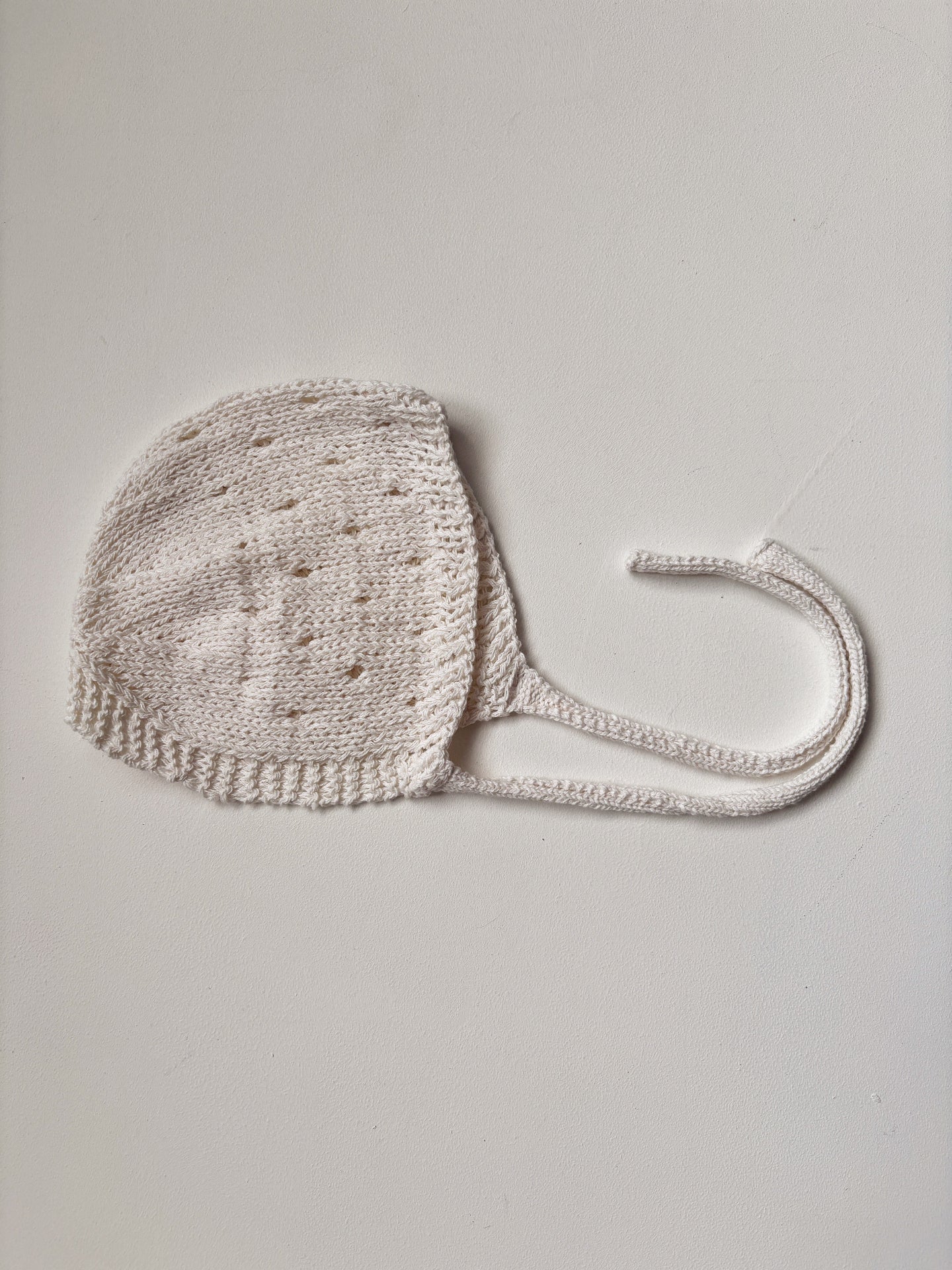 image shows a summer knitted baby bonnet in cream