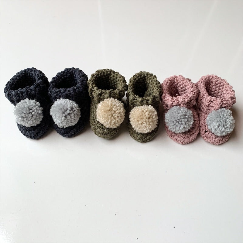 image shows three pairs of baby booties crocheted from organic cotton in navy, olive and pink