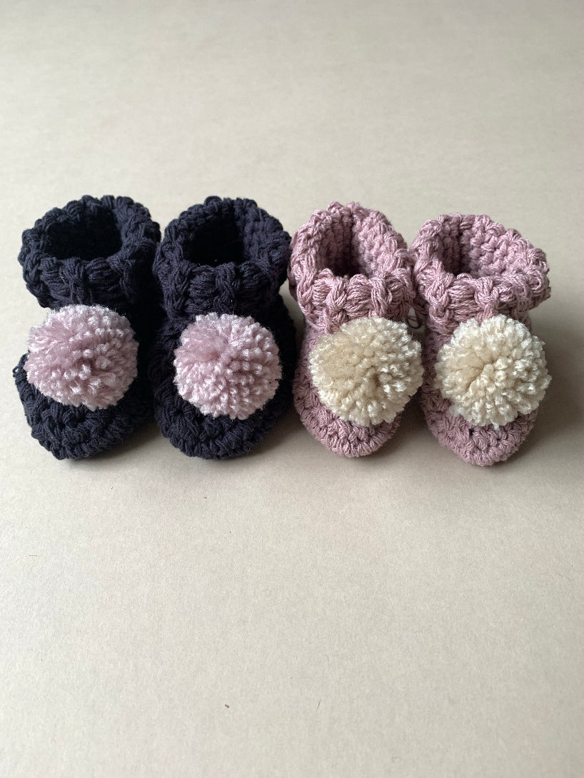 Image shows a pair of ink and chalky pink baby booties